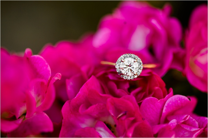 Large diamond engagement ring resting on a bright pink flower