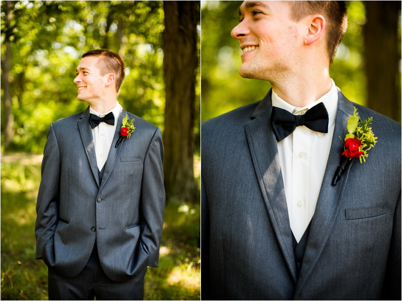 Groom portraits while wearing a dark grey suit with a back bowtie and a red boutonnière 
