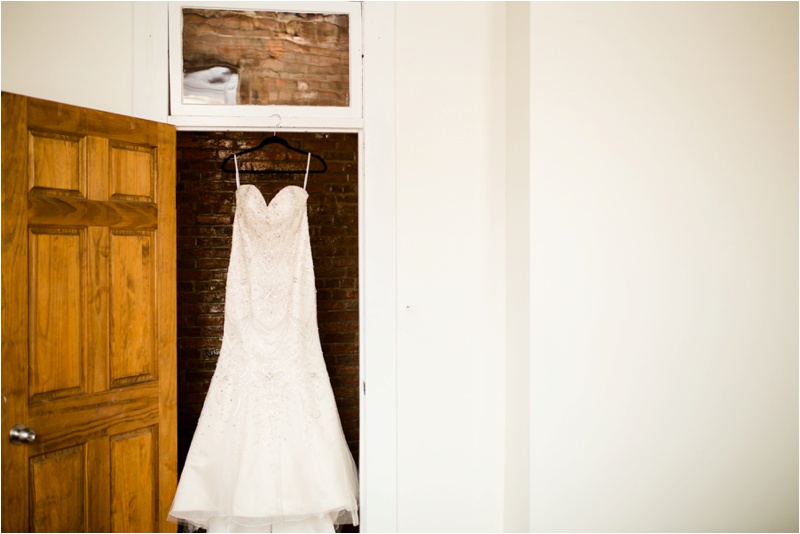 wedding dress hanging up in the doorway of a room with white walls and a wooden door