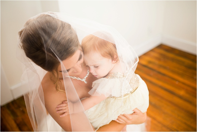 bride gently holds her daughter underneath her veil 