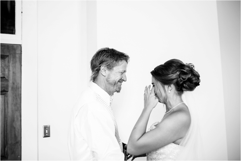 black and white picture of the brides dad smiling and holding the bride as she cries after her first look