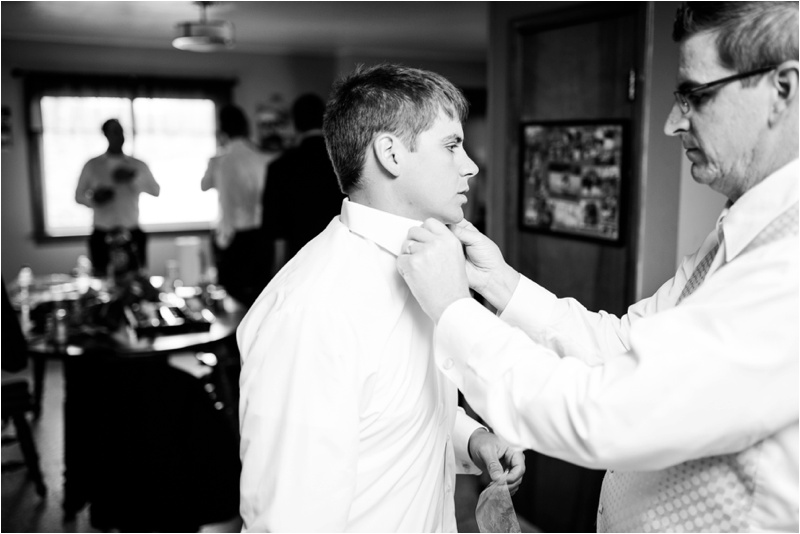black and white picture of the groom getting his tie straighten by his father