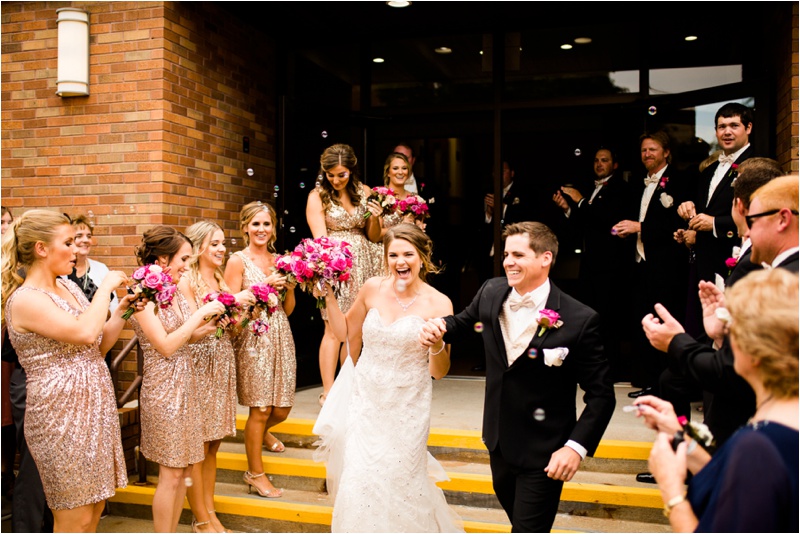 bride and groom exit their ceremony excitedly as the crowd cheers, clap, and blow bubbles