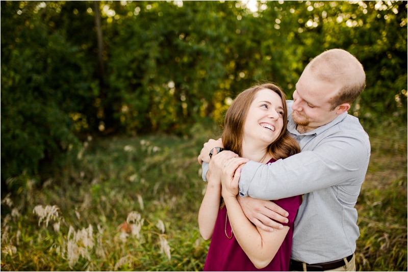 excited couple smiles at each other during engagement session