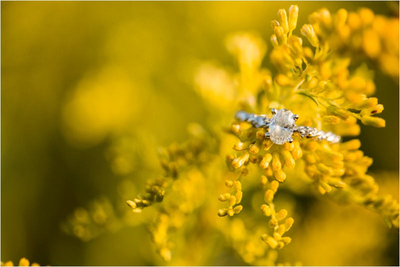 Diamond engagement ring resting on a yellow wildflower