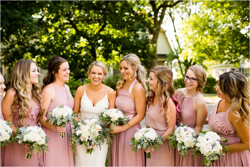 bridesmaids laughing as they take a picture with the bride