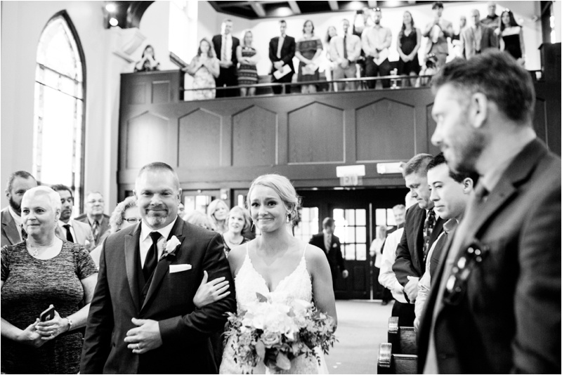bride getting emotional as she sees the groom at the end of the church aisle 