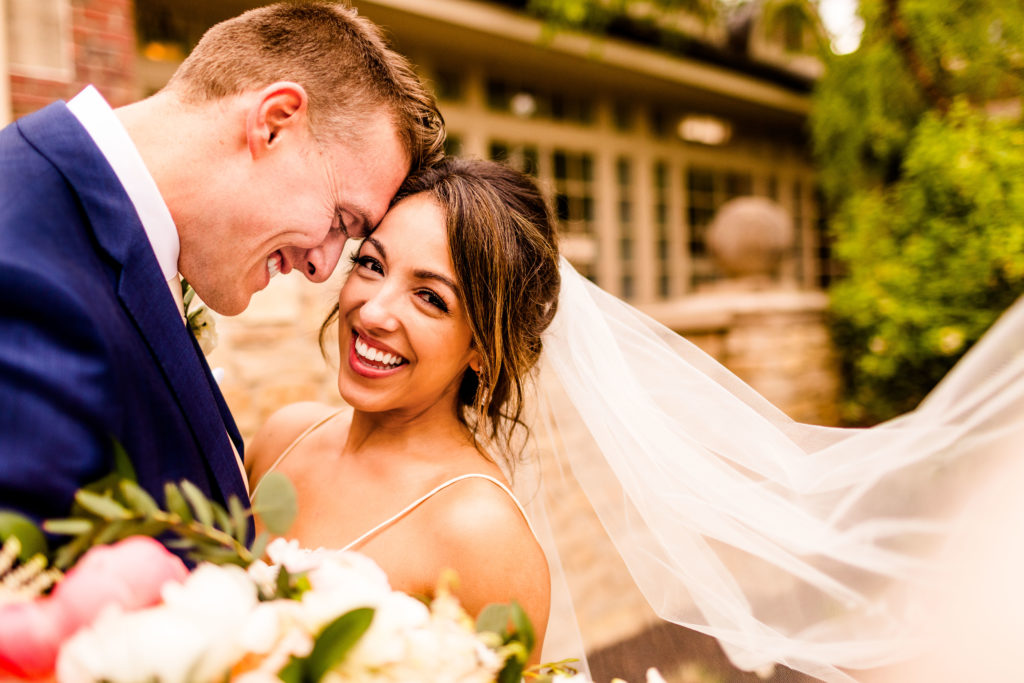 A joyful bride and groom embrace with her veil flowing, capturing a romantic wedding moment perfect for CloudSpot vs Pixieset photo delivery.







