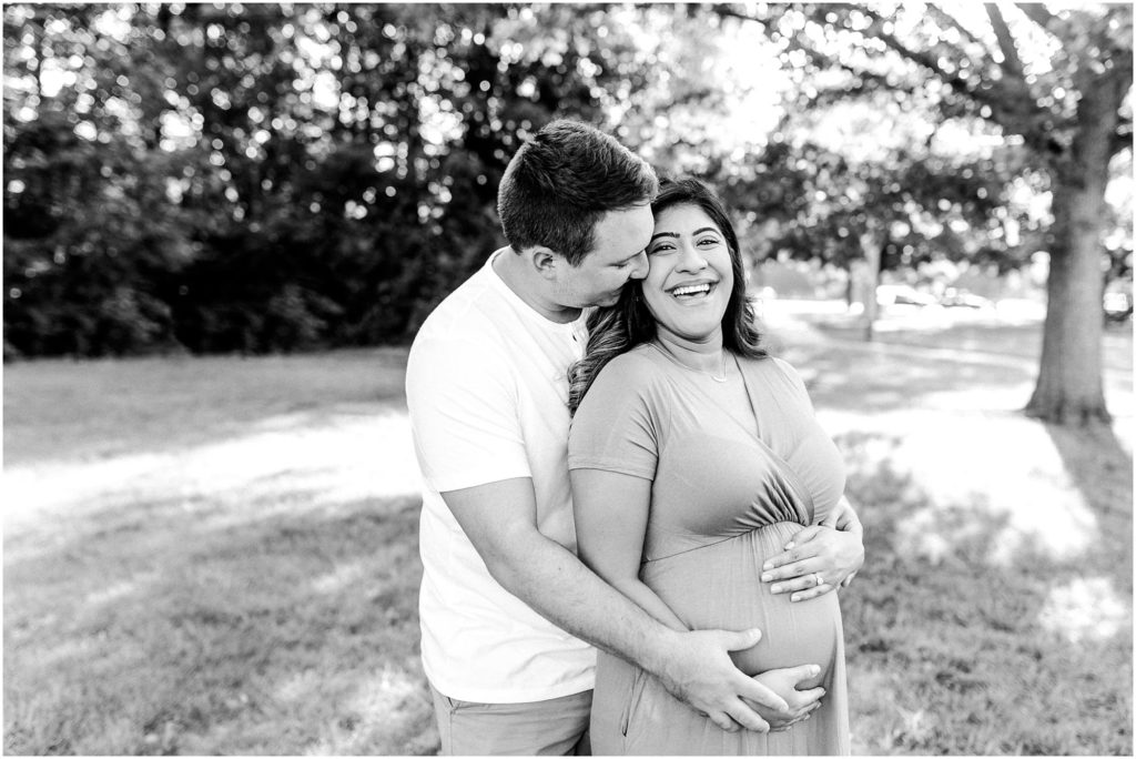 mom laughs during maternity photos in Ewing Park photographed by Bloomington IL maternity photographers Caitlin and Luke Photography