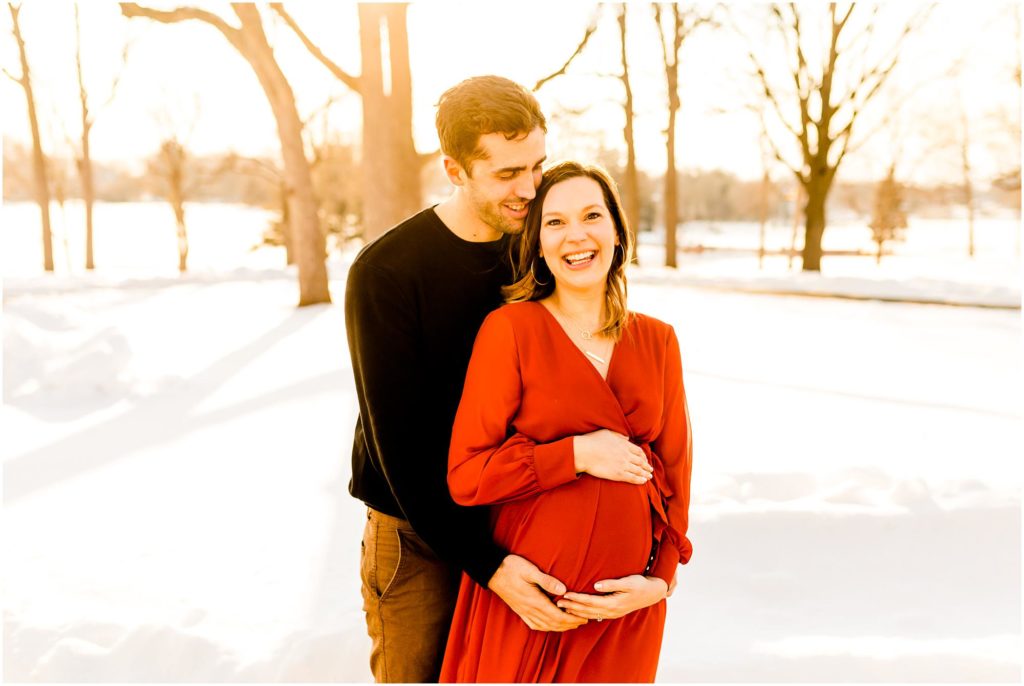 Bloomington Country Club maternity portraits with mother in red dress in the snow photographed by Illinois maternity photographers Caitlin and Luke Photography, IL maternity photographers