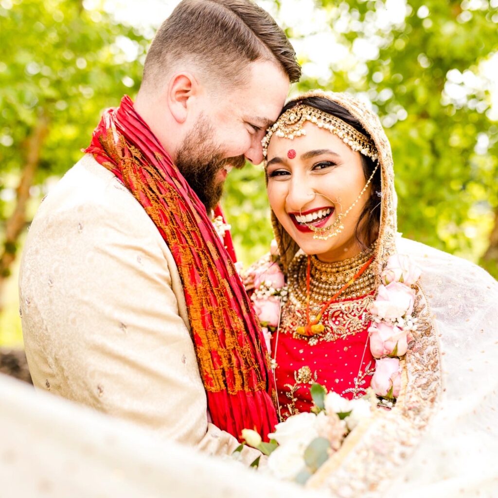 Joyful couple in traditional Indian wedding attire sharing intimate moment outdoors