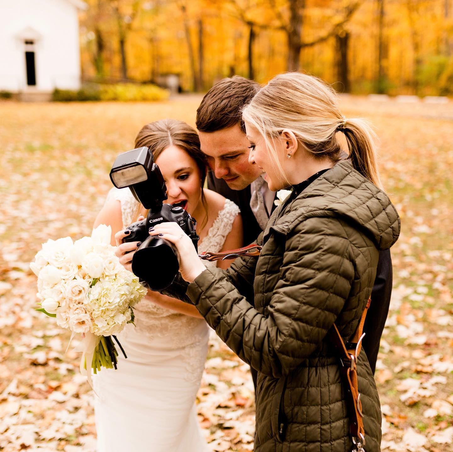 Caitlin showing the back of the camera to a bride and groom